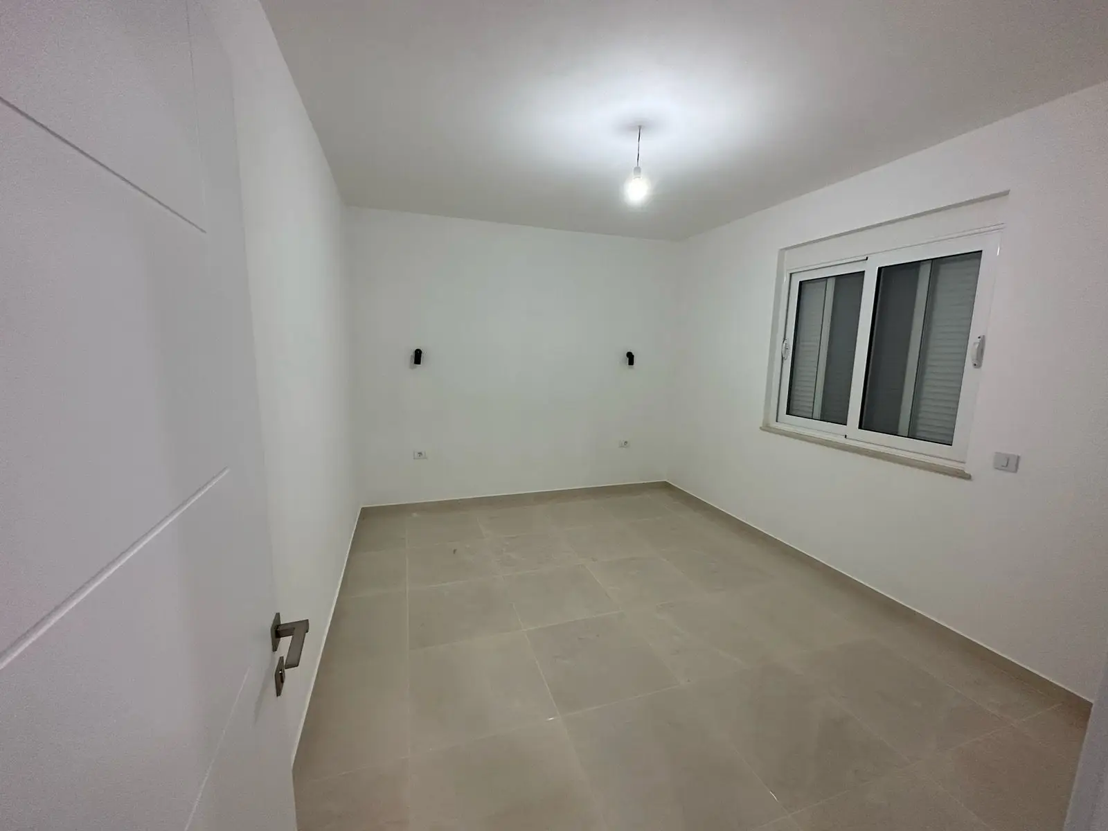 Modern, sunlit room in Ulcinj, Montenegro&mdash;ideal investment. White walls, tiled floor, window. Exclusive on immorenta.me by Ekosphere doo.