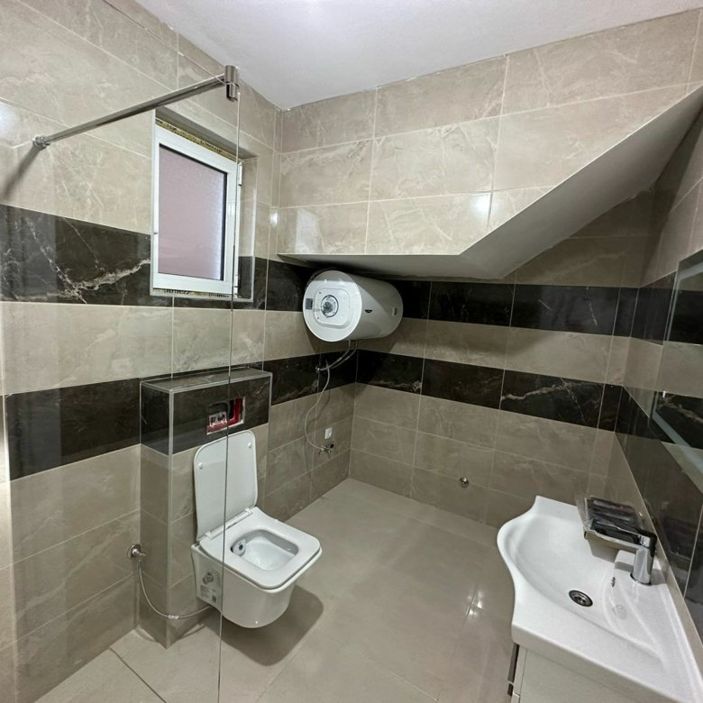 Modern bathroom in Ulcinj property with elegant tiles, glass shower, and premium fixtures. Exclusive on immorenta.me by ekosphere doo.