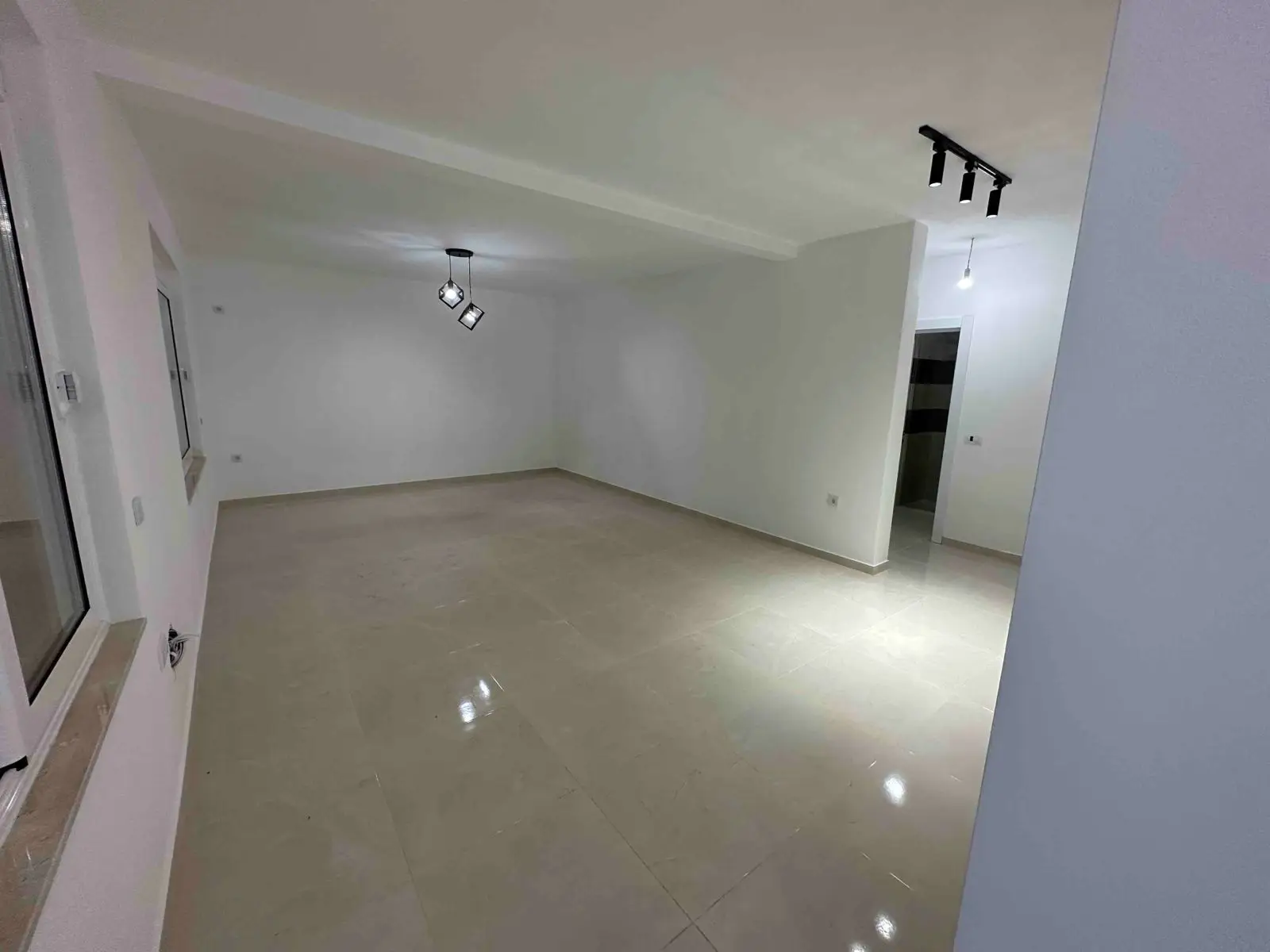 Modern, sunlit room with glossy beige tiles and white walls&mdash;prime Ulcinj property for sale on immorenta.me by ekosphere doo.