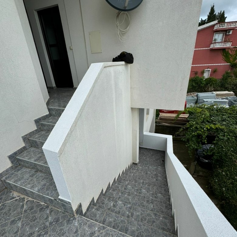 Premium Ulcinj property: tiled stairs, white wall with satellite, red building and lush greenery. immorenta.me by ekosphere doo.
