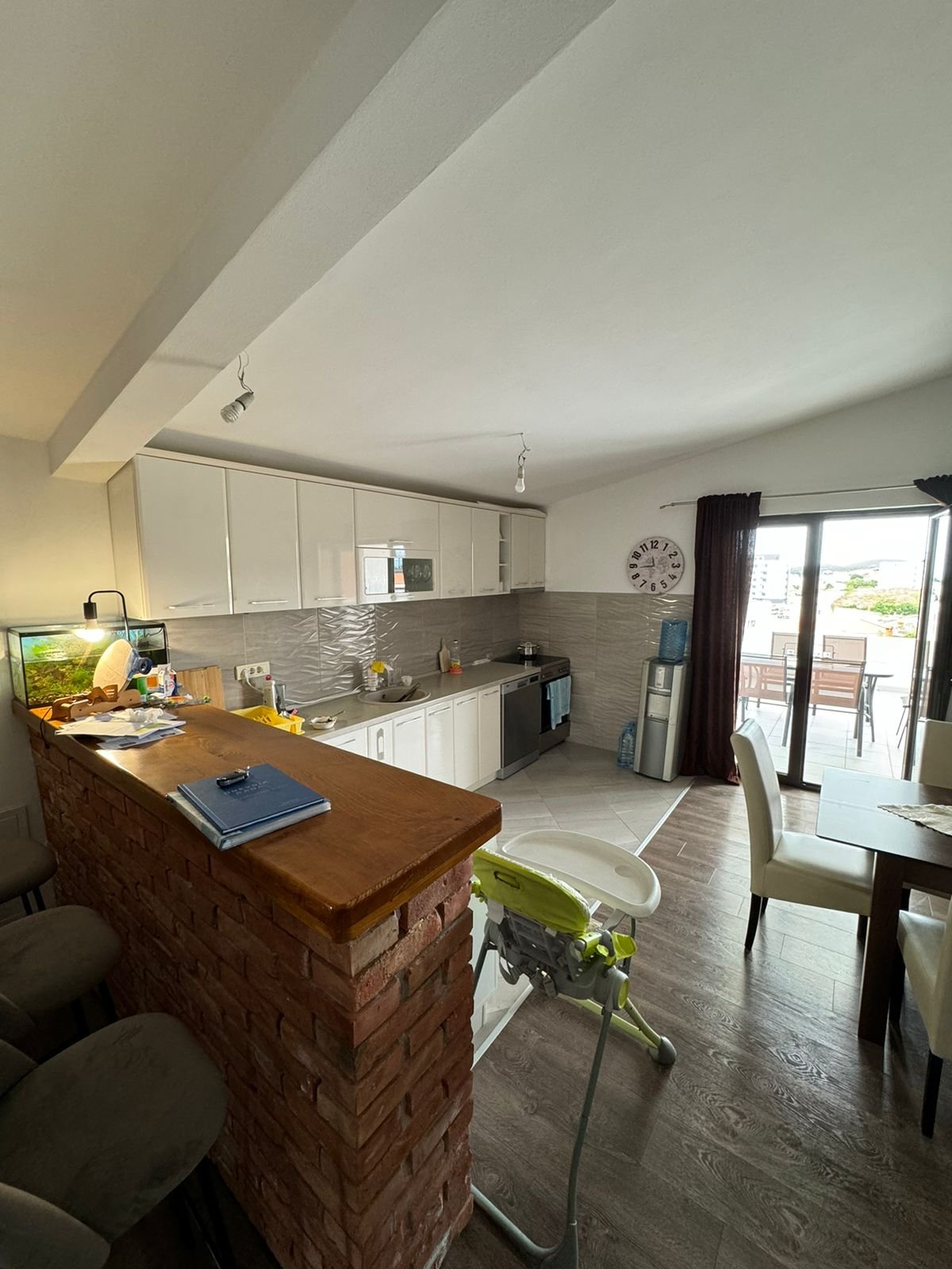 Stylish modern kitchen in Ulcinj with white cabinets, wooden floors, and brick bar&mdash;exclusive at immorenta.me by ekosphere doo.