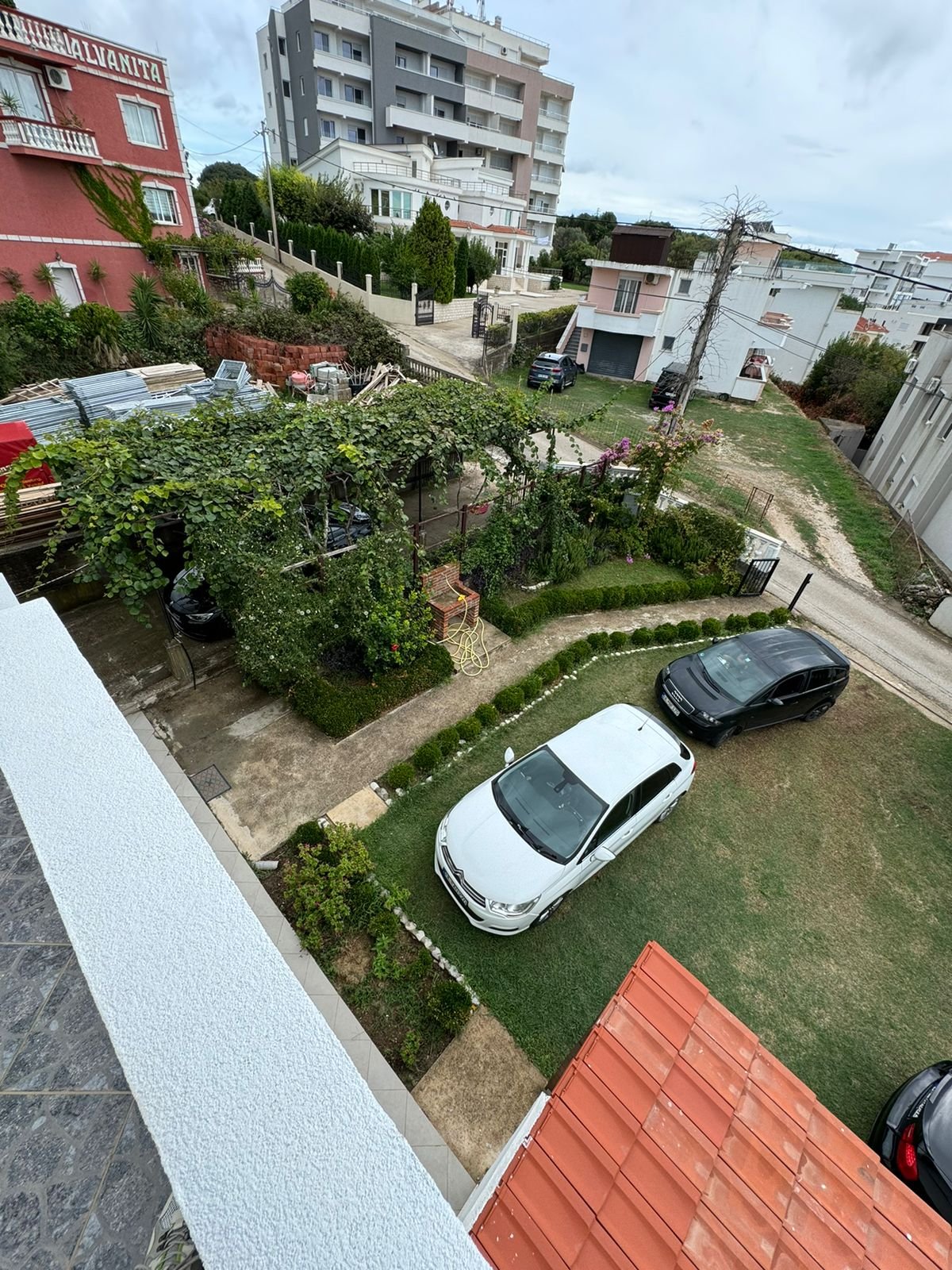 Aerial view of Ulcinj garden plot with pergola, cars, and nearby properties&mdash;prime real estate at immorenta.me by Ekosphere.