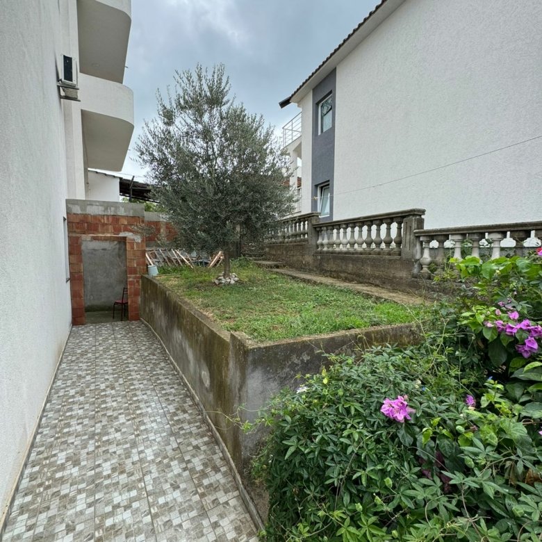 Elegant tiled walkway beside landscaped lawns, lush greenery, and flowers&mdash;prime Ulcinj property from ekosphere doo on immorenta.me.