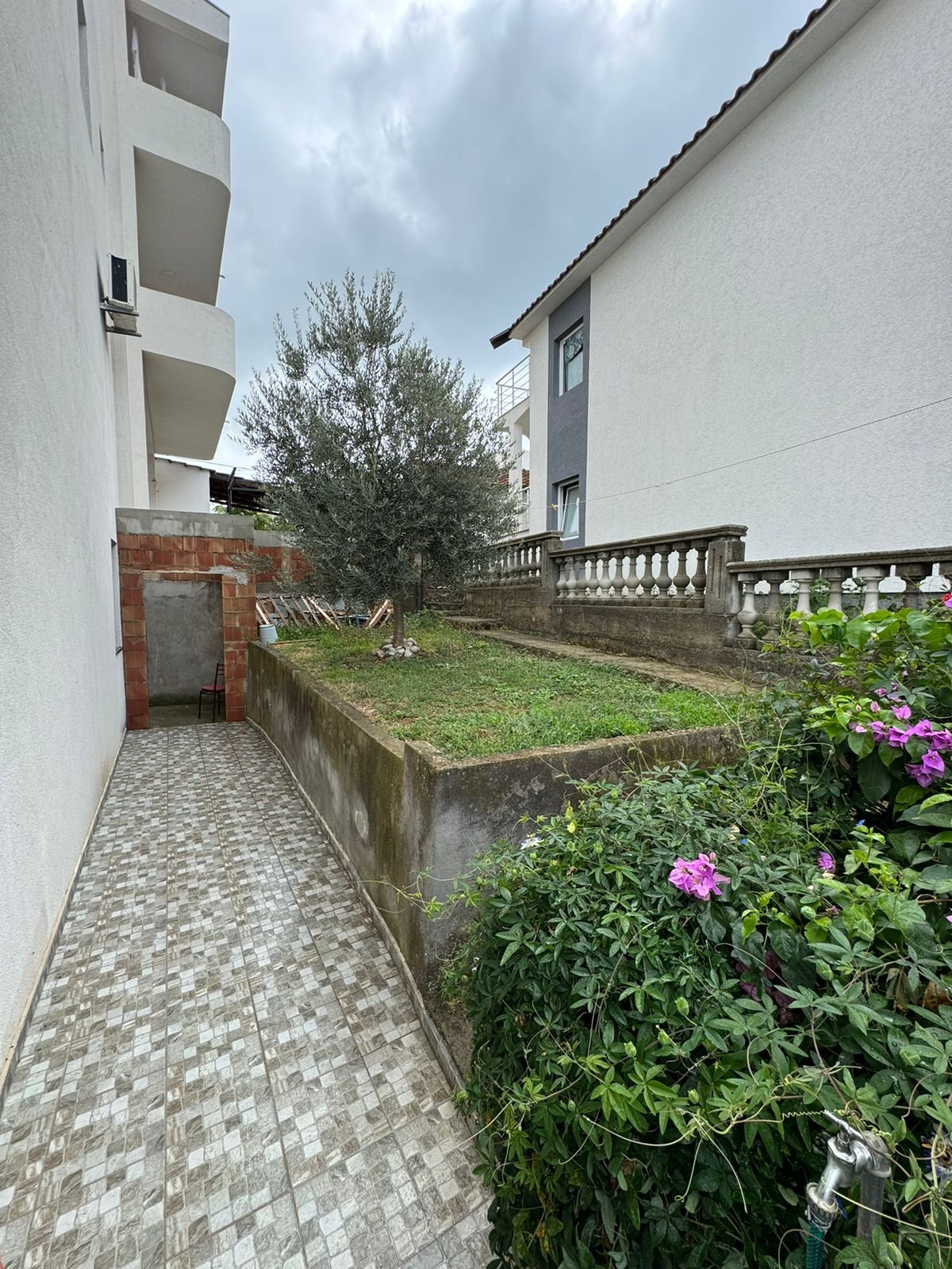 Elegant tiled walkway beside landscaped lawns, lush greenery, and flowers&mdash;prime Ulcinj property from ekosphere doo on immorenta.me.