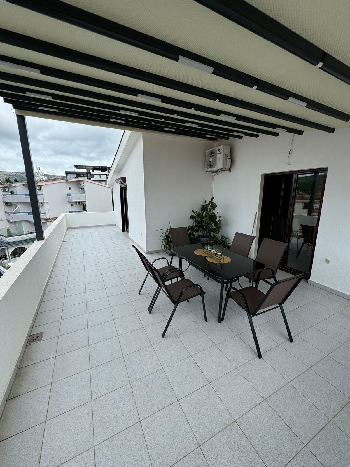 Modern outdoor terrace in Ulcinj, Montenegro with tiled flooring, stylish dining set, and covered roof&mdash;prime property by ekosphere doo.