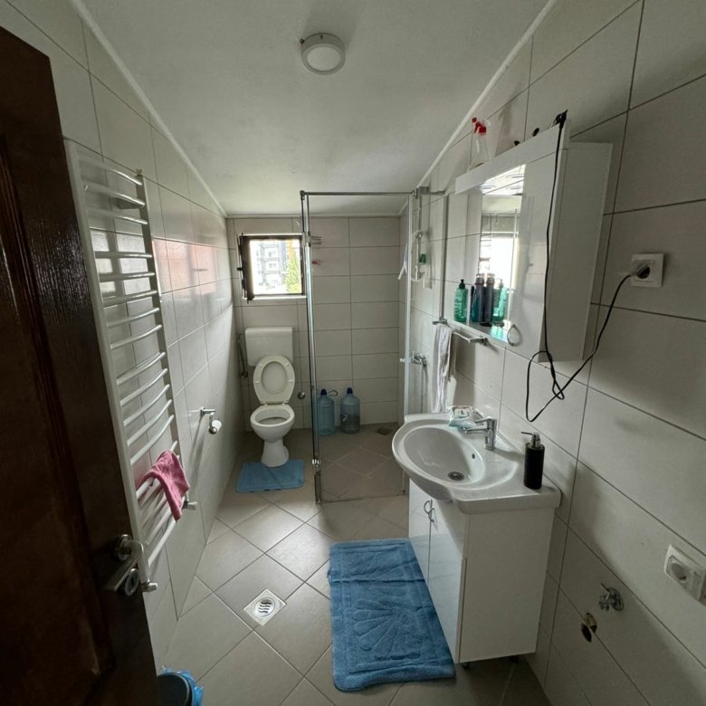 Modern Ulcinj property bathroom: white tiles, bright window, quality fixtures. Ideal investment on immorenta.me by ekosphere doo.