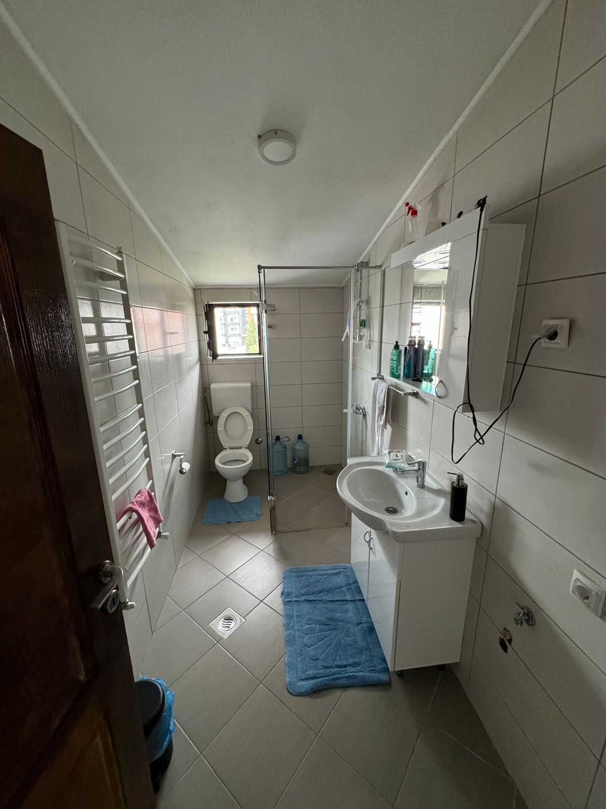 Modern Ulcinj property bathroom: white tiles, bright window, quality fixtures. Ideal investment on immorenta.me by ekosphere doo.