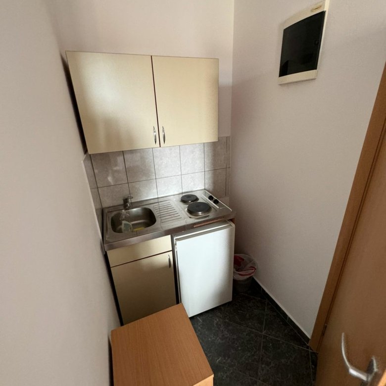 Modern kitchenette in Ulcinj with sink, cooktop, mini fridge, and sleek cabinets&mdash;ideal investment with immorenta.me by ekosphere doo.