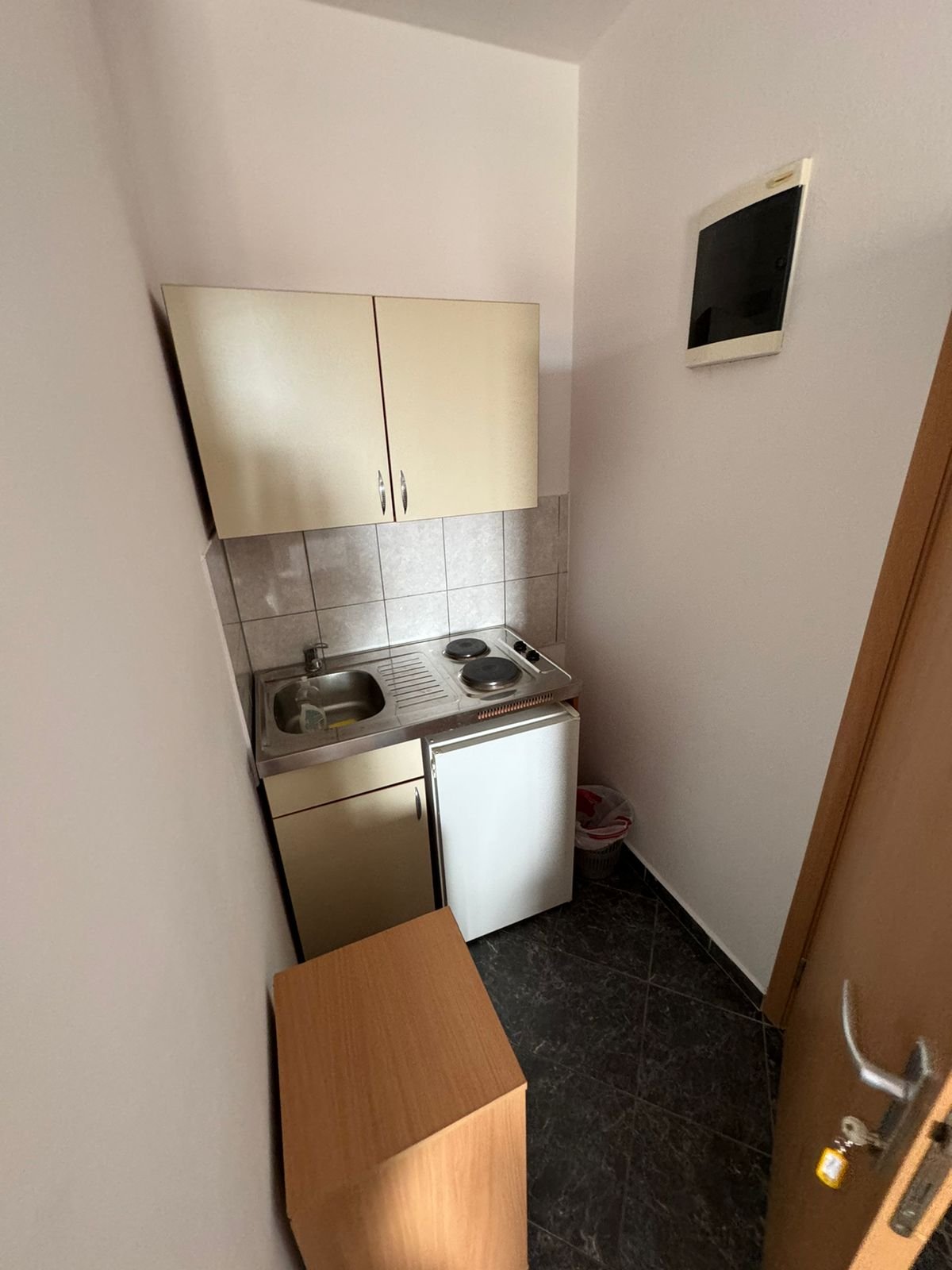Modern kitchenette in Ulcinj with sink, cooktop, mini fridge, and sleek cabinets&mdash;ideal investment with immorenta.me by ekosphere doo.
