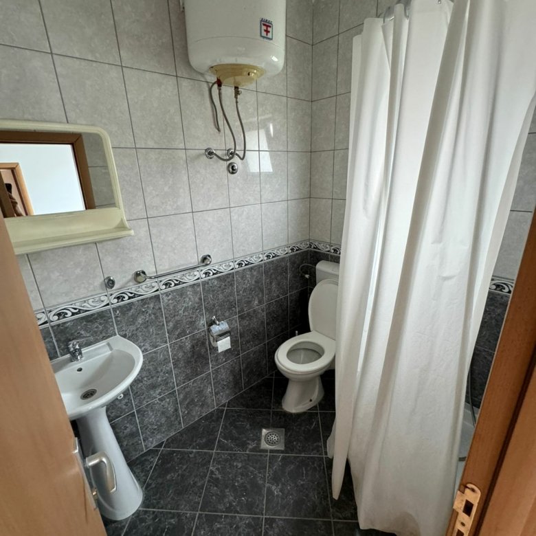 Modern grey-tiled bathroom in Ulcinj property: sink, mirror, shower, heater. Invest via immorenta.me by ekosphere doo.
