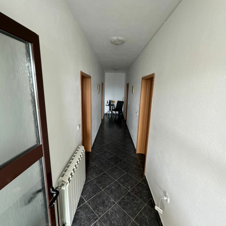 Elegant hallway with white walls, black tiled floors, three wood doorways&mdash;ideal Ulcinj real estate by Ekosphere on immorenta.me.