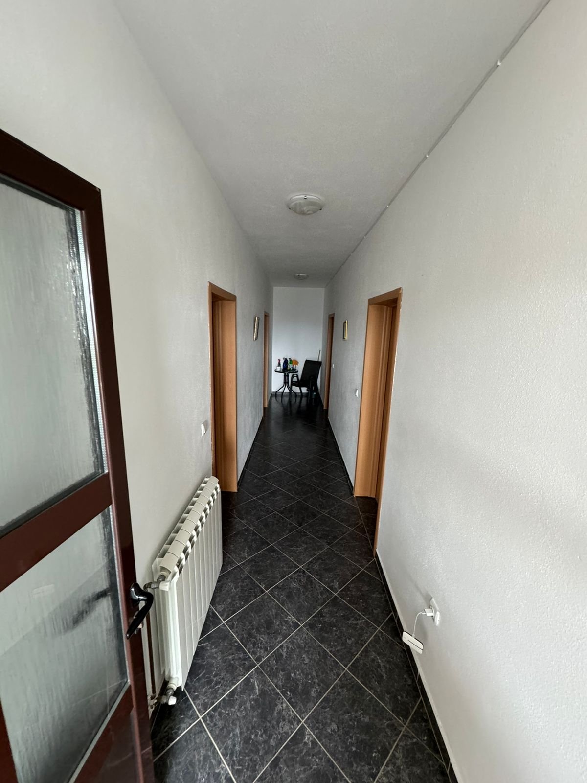 Elegant hallway with white walls, black tiled floors, three wood doorways&mdash;ideal Ulcinj real estate by Ekosphere on immorenta.me.