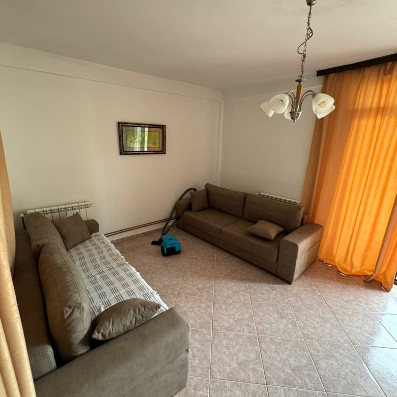 Spacious Ulcinj living room with 2 brown sofas, tiled floors, large sunny window&mdash;exclusive Montenegro real estate by ekosphere doo.