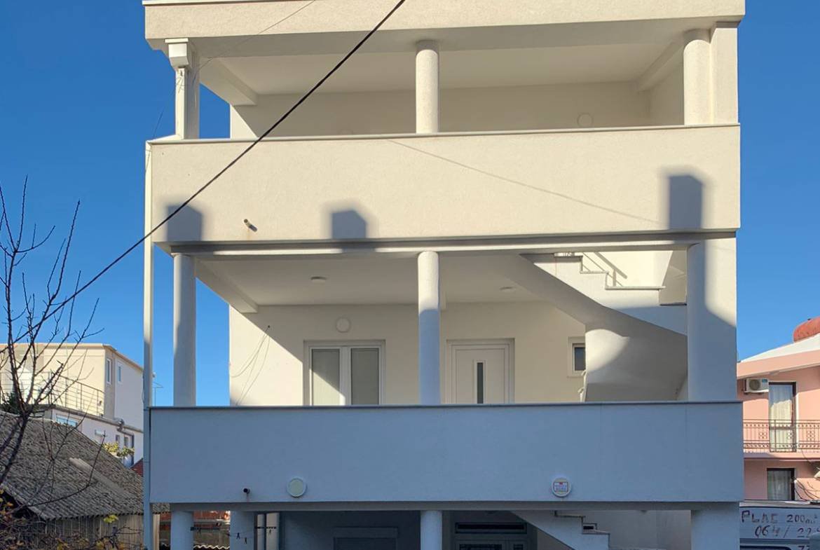 Elegant three-story white property with balconies, pillars, and spiral staircase in sunny Ulcinj. Exclusive on immorenta.me by ekosphere doo.