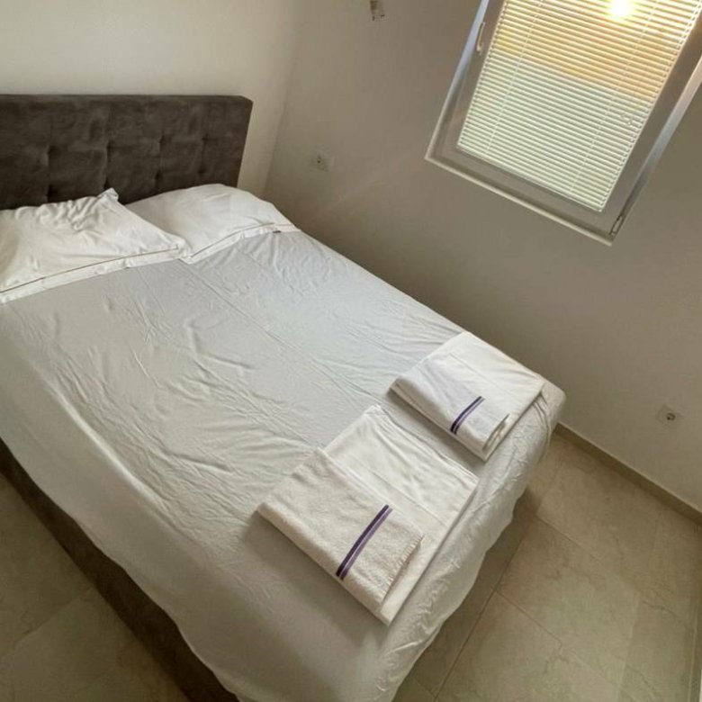 Modern Ulcinj bedroom with double bed, crisp linens, nightstand, window&mdash;prime real estate by ekosphere doo on immorenta.me.