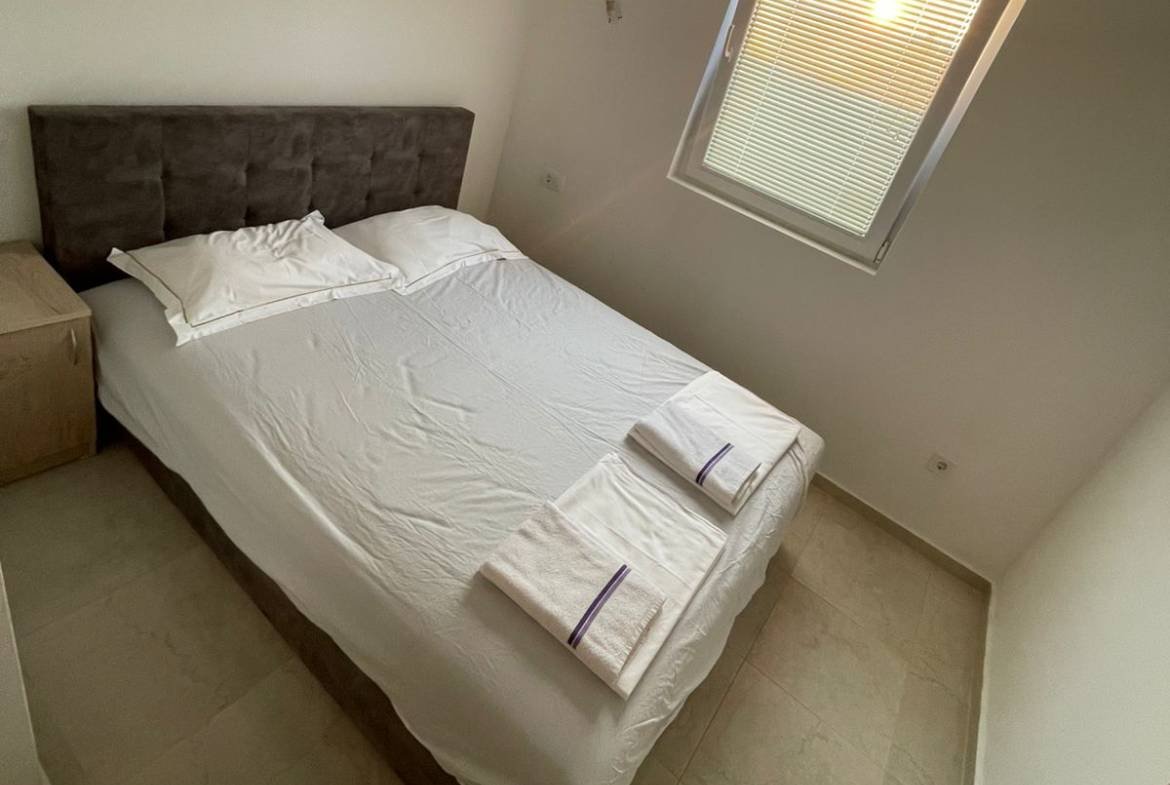 Modern Ulcinj bedroom with double bed, crisp linens, nightstand, window&mdash;prime real estate by ekosphere doo on immorenta.me.