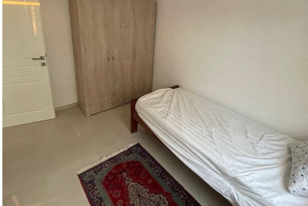 Modern, airy Ulcinj bedroom with white bed, wardrobe, and rug&mdash;ideal Montenegro property investment by Ekosphere on immorenta.me.