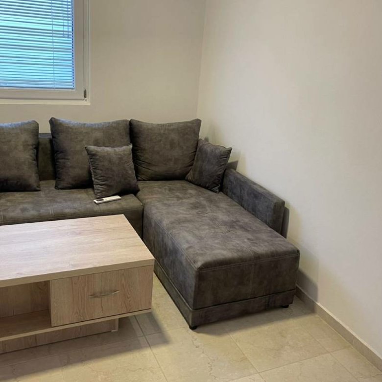 Modern Ekosphere home in Ulcinj: gray L-shaped sofa, wood coffee table, window blinds&mdash;exclusive at immorenta.me by Ekosphere doo.