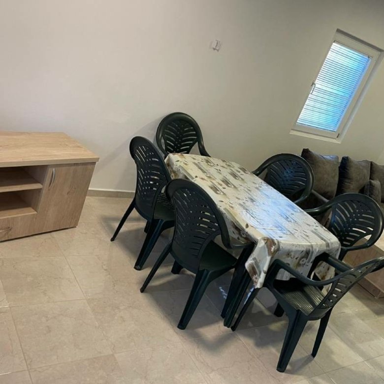 Modern Ulcinj property dining area with sleek table, six black chairs, sofa, and wood details&mdash;exclusive at immorenta.me.