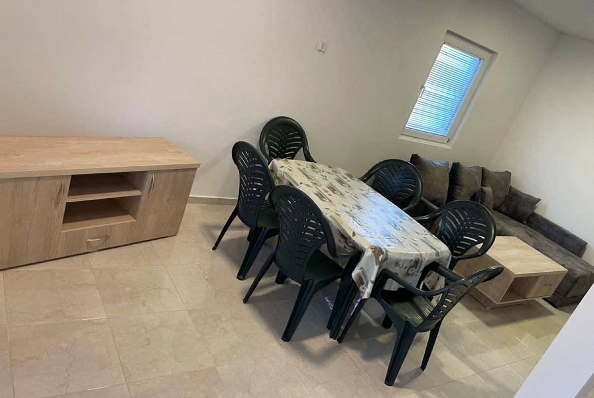 Modern Ulcinj property dining area with sleek table, six black chairs, sofa, and wood details&mdash;exclusive at immorenta.me.