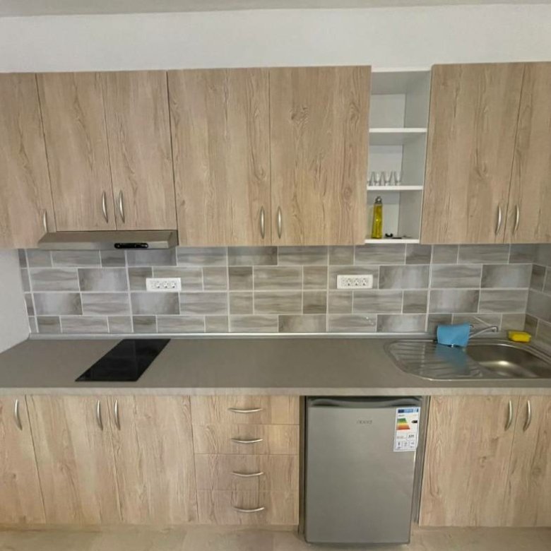 Modern Ulcinj kitchen with light wood cabinets, sleek backsplash, and cooktop&mdash;ideal property investment on immorenta.me by ekosphere doo.