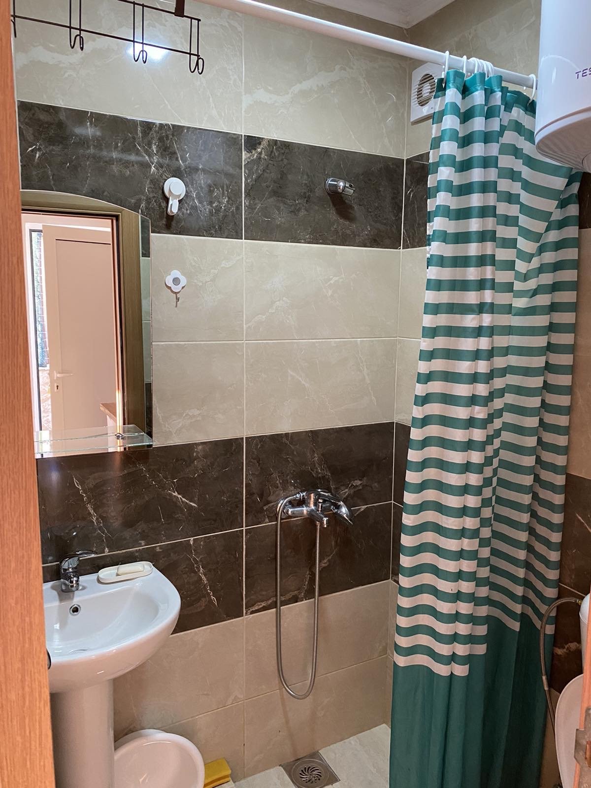 Modern Ulcinj bathroom with stylish beige/dark brown tiles, shower, sink, and water heater&mdash;ideal real estate on immorenta.me.