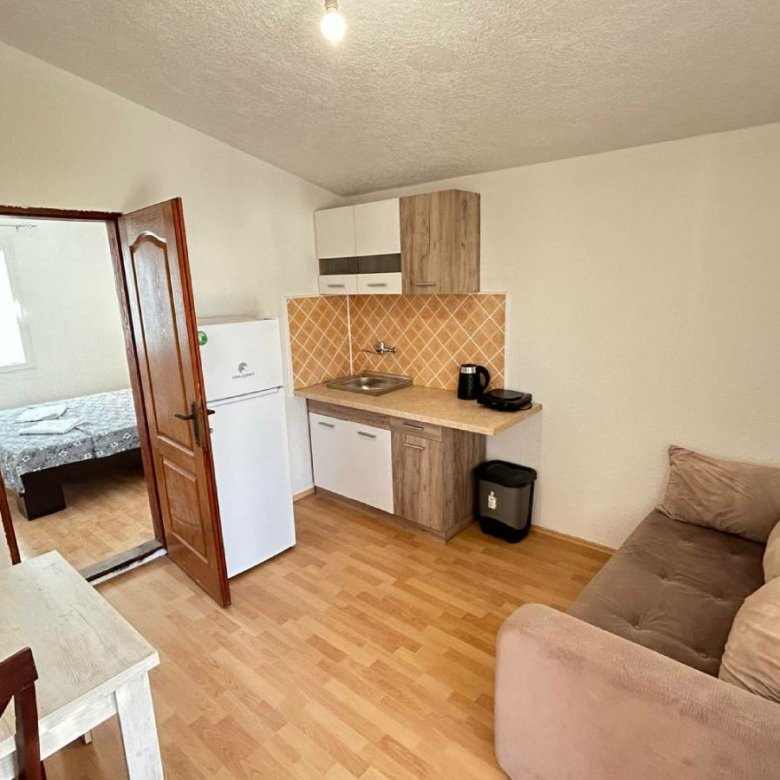 Modern Ulcinj apartment for sale: open kitchen, brown sofa, dining area, wood floors. Invest via immorenta.me by ekosphere doo.