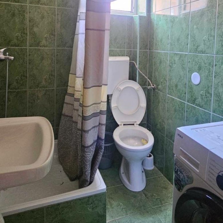 Modern green-tiled bathroom in Ulcinj with shower, washing machine, and natural light&mdash;prime real estate on immorenta.me by Ekosphere.