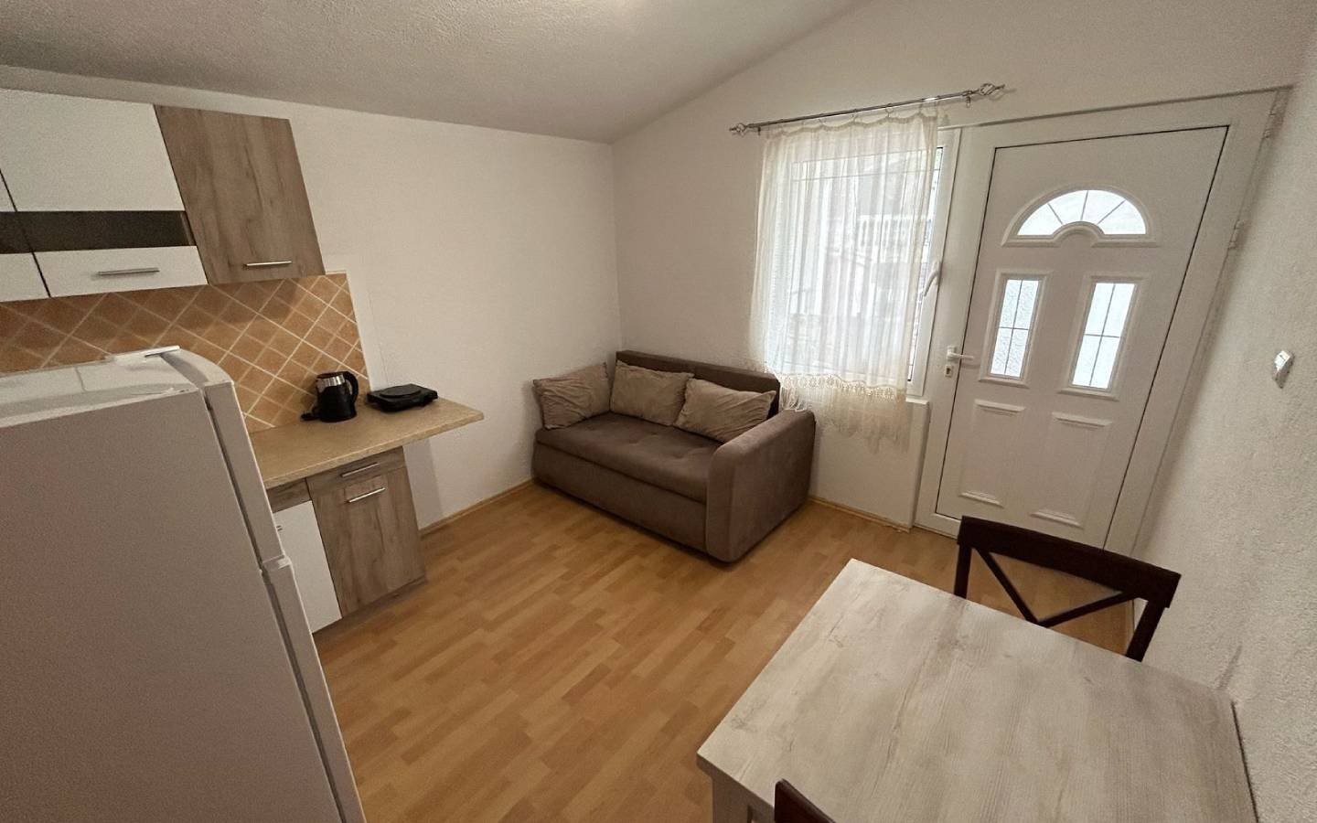 Modern Ulcinj studio with light wood floors, compact kitchen, and cozy furnishings&mdash;prime real estate via immorenta.me by ekosphere doo.