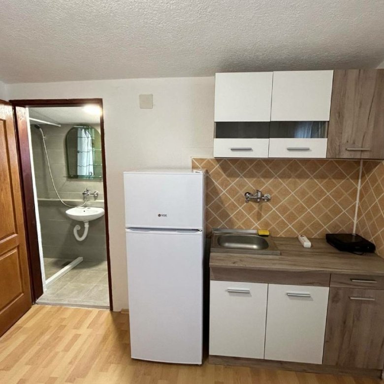 Modern compact kitchen in Ulcinj, Montenegro with appliances, stylish backsplash, and ensuite bath&mdash;exclusive at immorenta.me by Ekosphere.