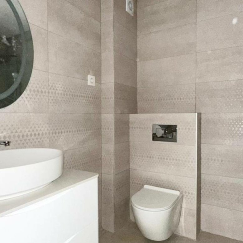 Stylish modern bathroom in luxury Ulcinj property: beige tiles, wall-mounted toilet, round mirror, and chic vanity. immorenta.me by ekosphere doo.