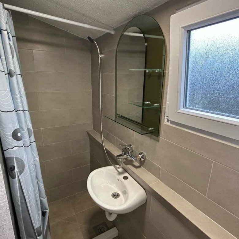 Modern Ulcinj bathroom with beige tiles, quality fixtures, and glass shelves&mdash;exclusive listing by ekosphere doo at immorenta.me.