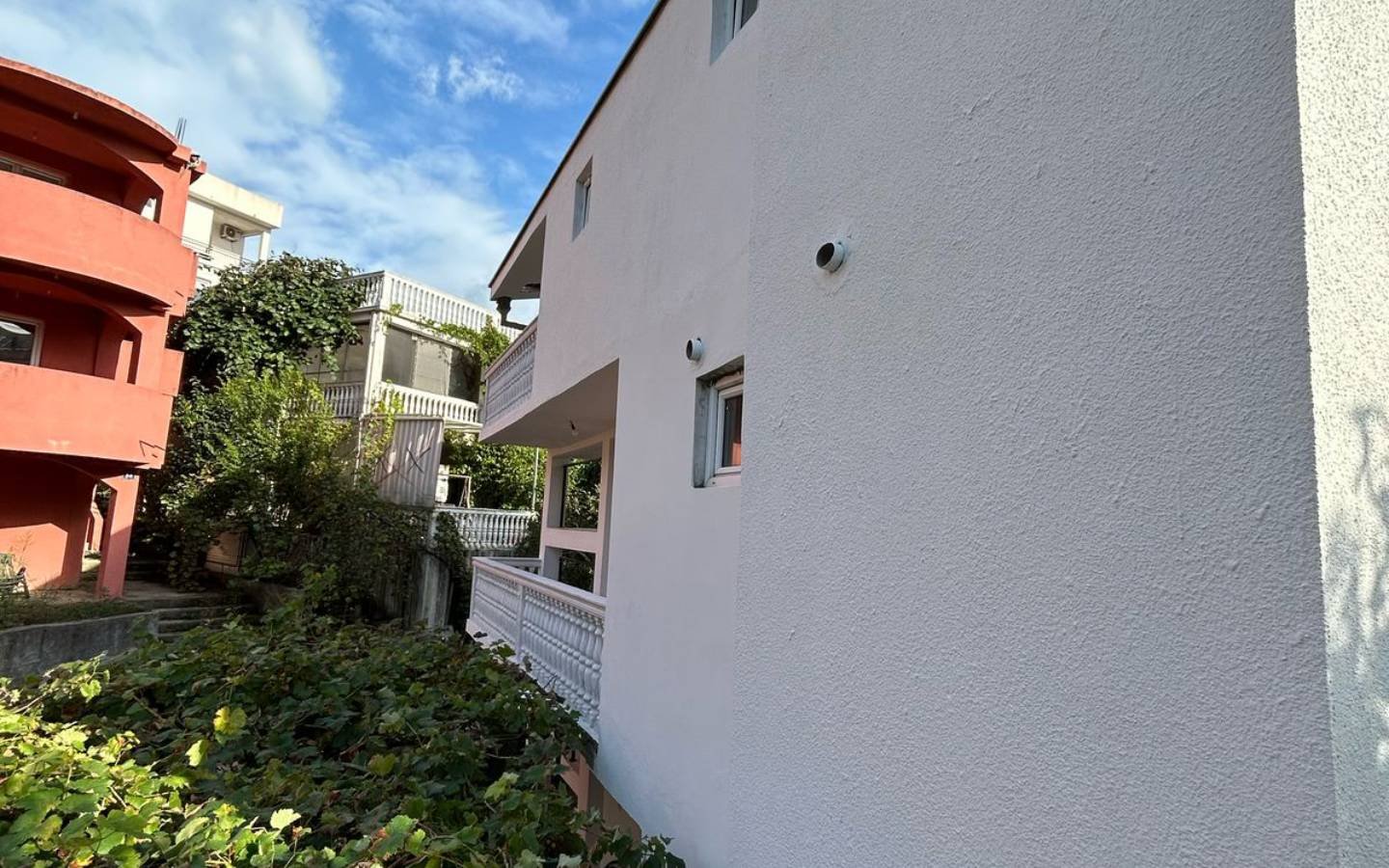 Modern white property in Ulcinj, Montenegro with balconies, security cameras, and lush greenery&mdash;exclusive on immorenta.me by Ekosphere doo.