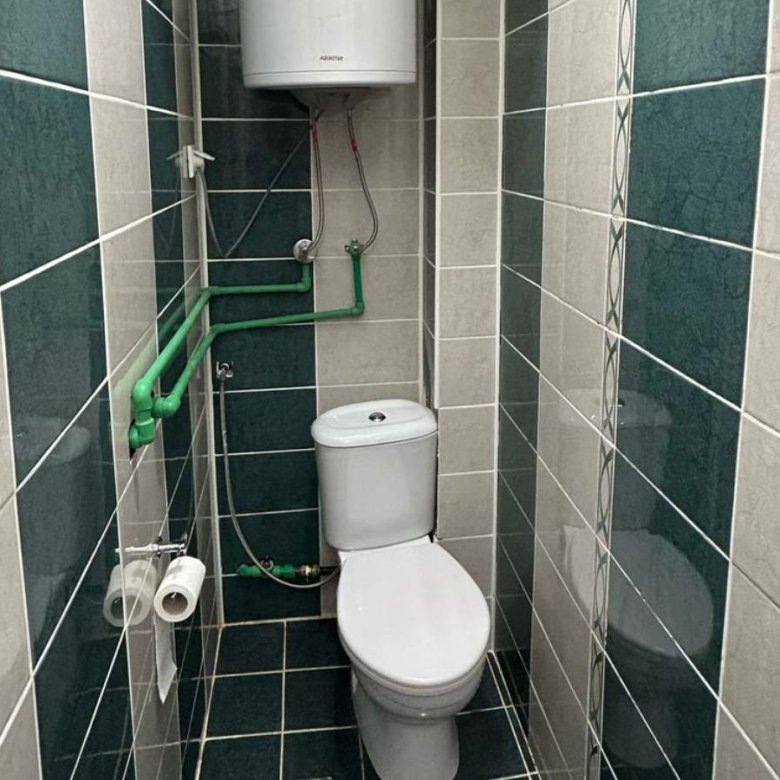 Modern narrow bathroom in Ulcinj property with tiled walls, white toilet, water heater; invest with immorenta.me by ekosphere doo.