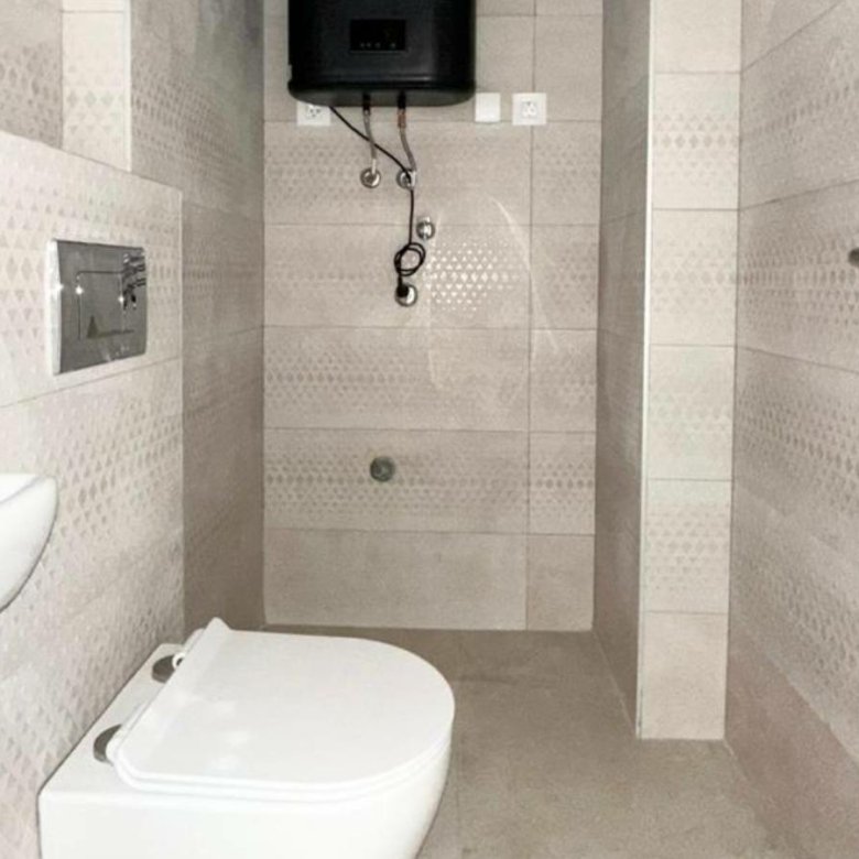 Modern tiled bathroom with wall-mounted toilet, corner sink, and water heater&mdash;ideal Ulcinj Montenegro investment. Montenegro-listings.me by Ekosphere.