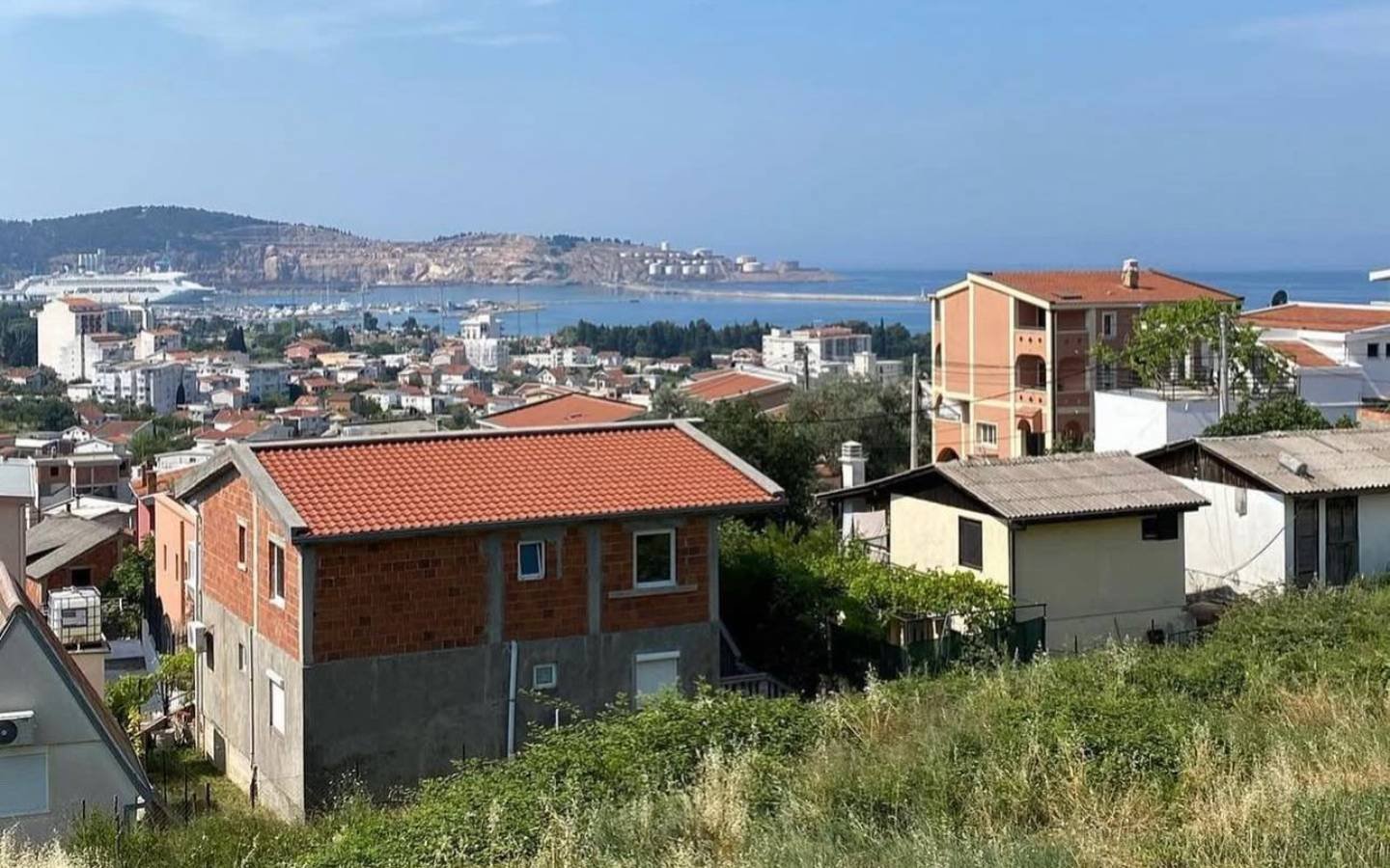 Panoramic Ulcinj, Montenegro: red-roof homes, lush greenery, harbor views&mdash;premium real estate by Ekosphere on immorenta.me.
