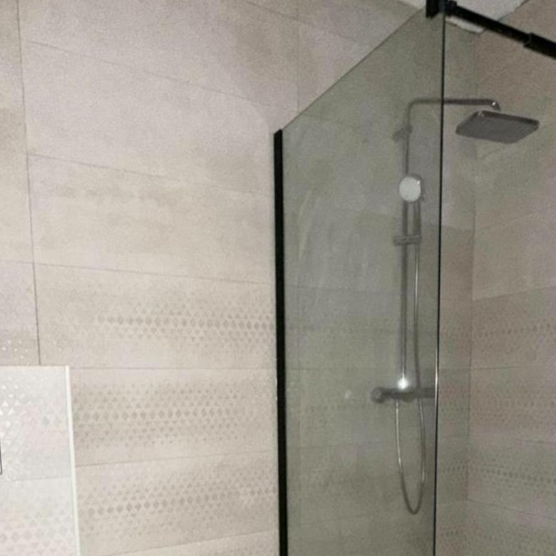 Sleek Ulcinj bathroom with light tiles, glass shower, rainfall head&mdash;prime Montenegro real estate by ekosphere doo on immorenta.me.