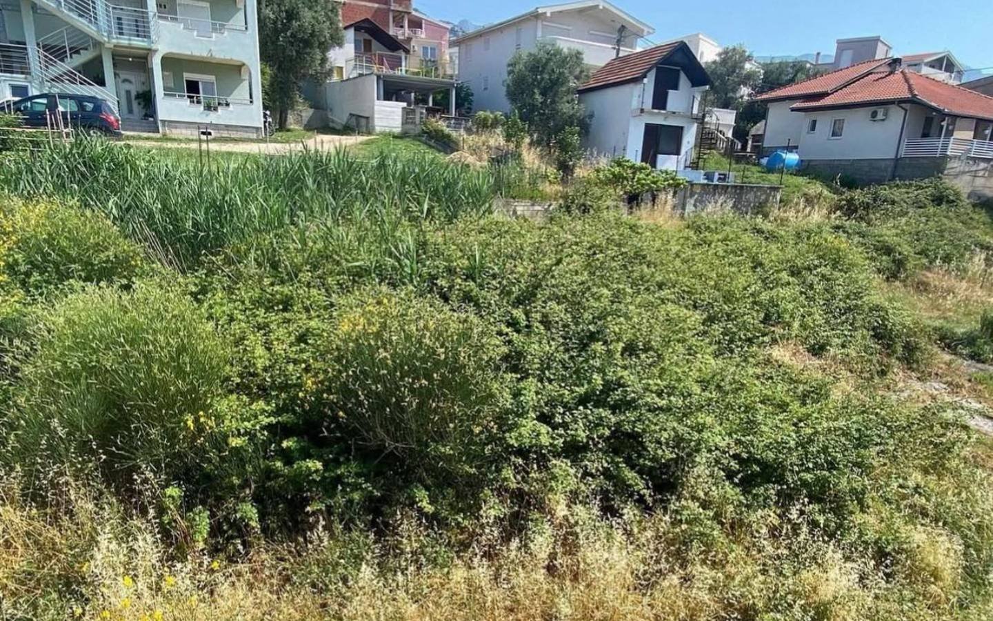 Prime investment opportunity: spacious, overgrown Ulcinj lot near modern homes&mdash;ideal for development; featured by immorenta.me, a project of Ekosphere doo.