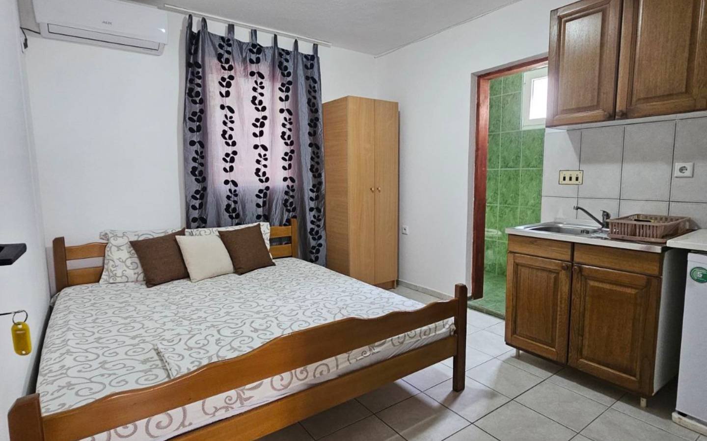 Modern Ulcinj studio: wooden bed, chic kitchenette, green-tiled bath. Smart eco-investment by Ekosphere on immorenta.me.