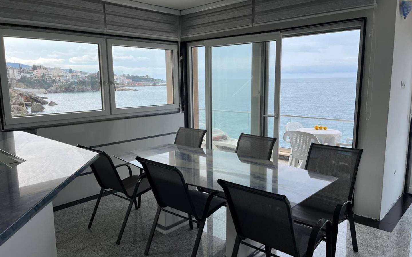 Elegant dining area with glass table, sea views, and modern design in Ulcinj&mdash;exclusive real estate from immorenta.me by Ekosphere.