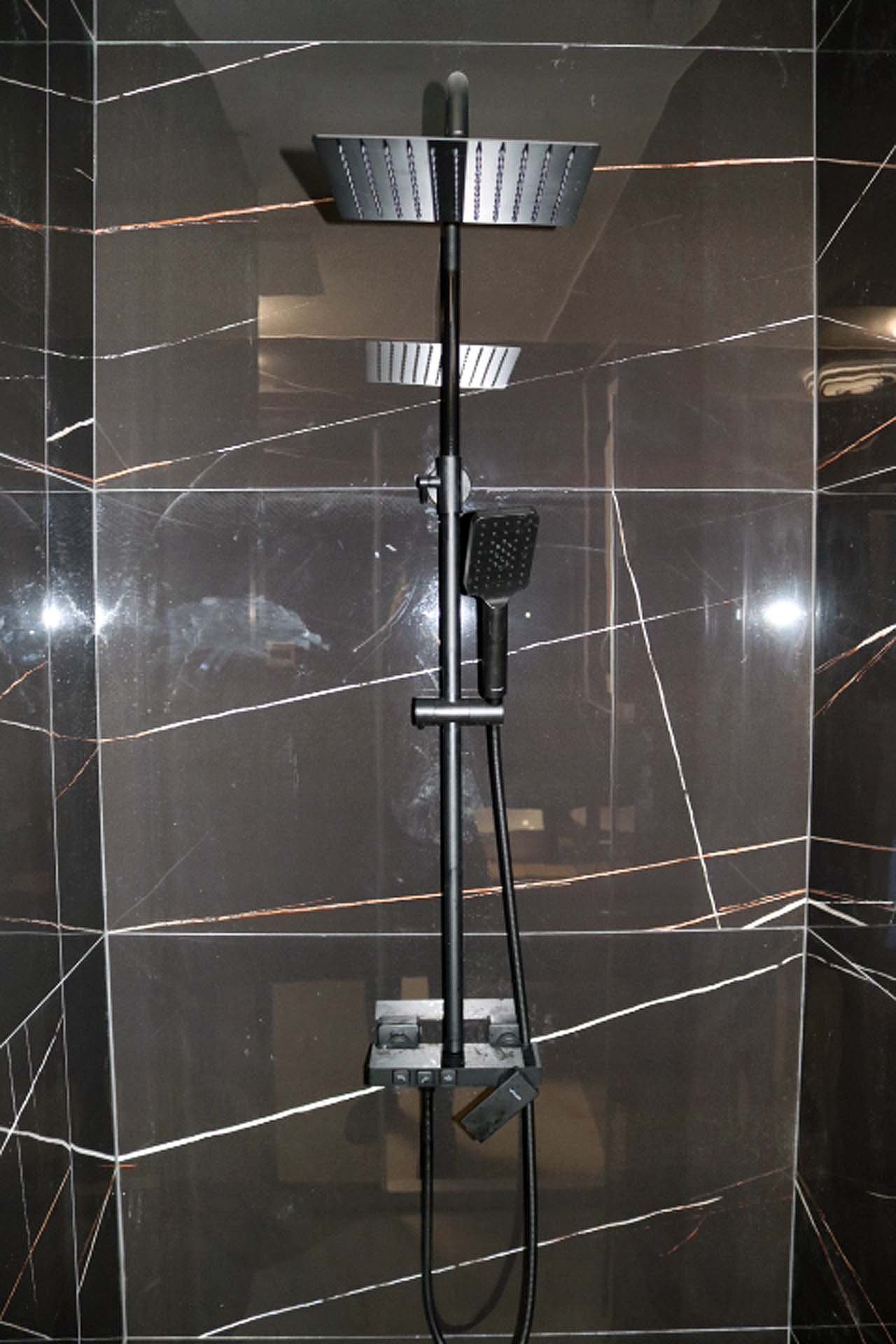 Luxurious Ulcinj bathroom featuring a modern rain shower, black fixtures, and elegant dark tiles&mdash;exclusive on immorenta.me by ekosphere doo.