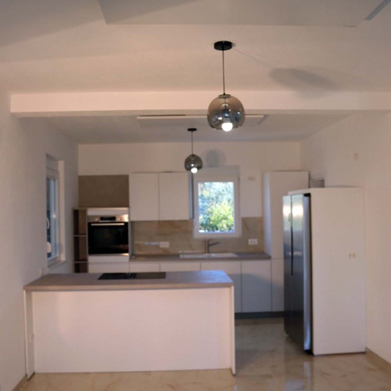 Stylish Adana Villa kitchen with sleek white cabinets, island cooktop, marble tiles&mdash;prime Ulcinj investment on immorenta.me by ekosphere doo.