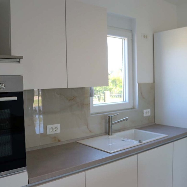 Contemporary Ulcinj villa kitchen with sleek white cabinetry, modern appliances, and premium finishes&mdash;exclusive from immorenta.me.