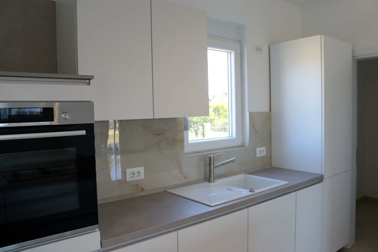 Contemporary Ulcinj villa kitchen with sleek white cabinetry, modern appliances, and premium finishes&mdash;exclusive from immorenta.me.