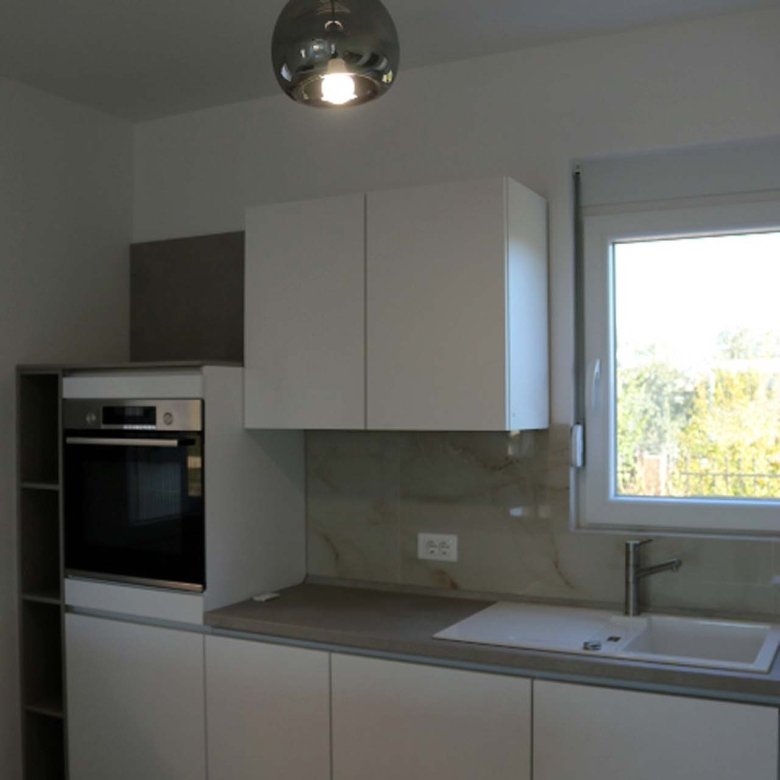 Stylish Adana Villa kitchen in Ulcinj: white cabinets, built-in oven, windowed sink, grey countertops&mdash;exclusive at immorenta.me by ekosphere doo.