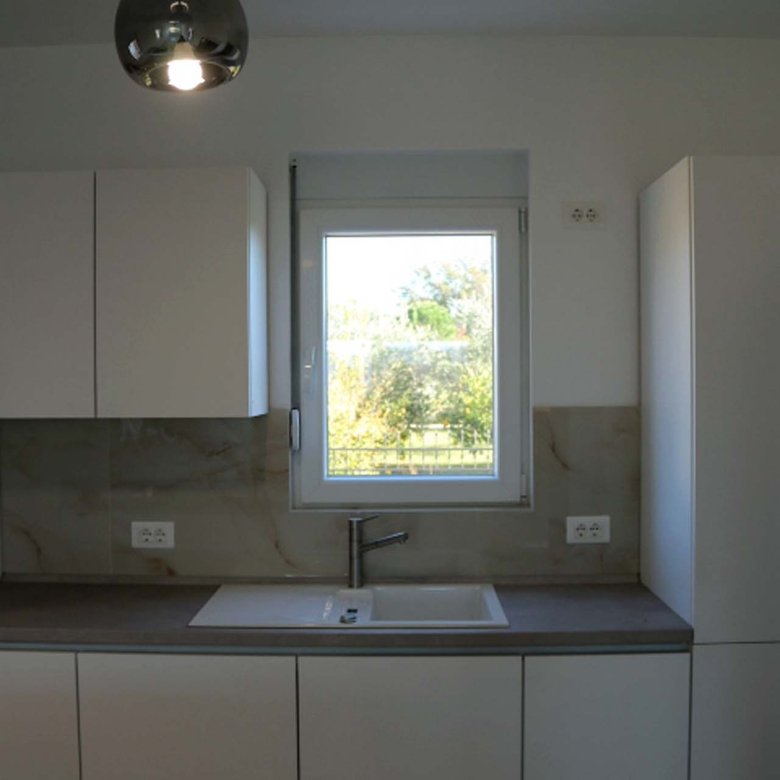 Experience luxury living in Ulcinj, Montenegro with this modern kitchen&mdash;white cabinets, natural light, and premium finishes.