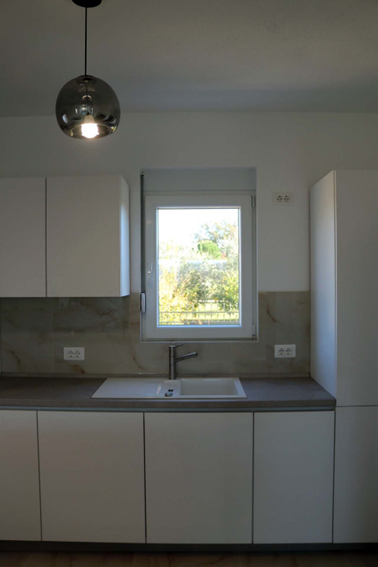 Experience luxury living in Ulcinj, Montenegro with this modern kitchen&mdash;white cabinets, natural light, and premium finishes.