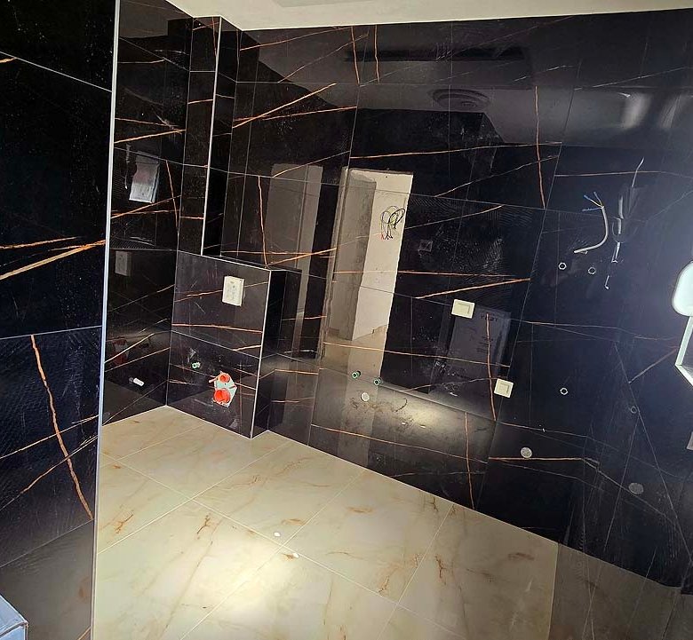 Modern bathroom in Ulcinj, Montenegro&mdash;black orange-streaked walls, beige tiles, sunlit window. Exclusive on immorenta.me by ekosphere doo.