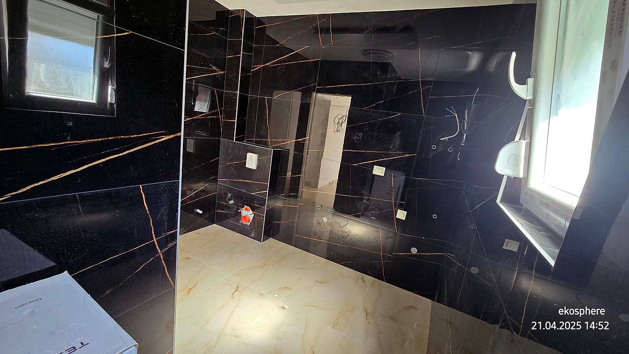 Modern bathroom in Ulcinj, Montenegro&mdash;black orange-streaked walls, beige tiles, sunlit window. Exclusive on immorenta.me by ekosphere doo.