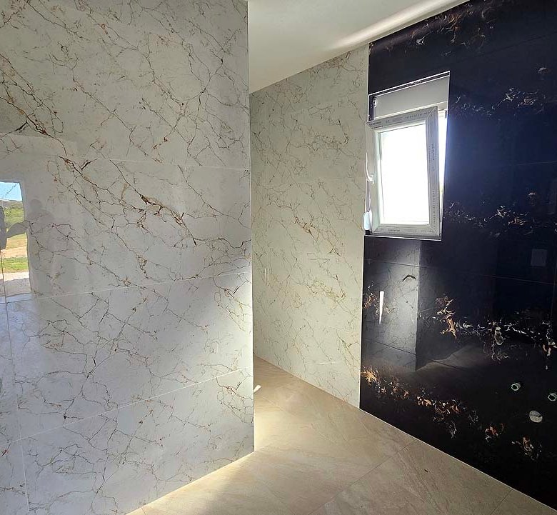 Modern bathroom in Ulcinj features marble tiles, black accent wall, natural light. Top Montenegro real estate by Ekosphere, on immorenta.me.
